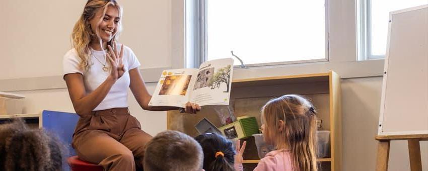 An early care and education students reads to toddlers in a child development center on campus.